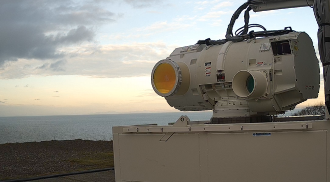 DragonFire laser weapon mounted on a box with a sunset behind it