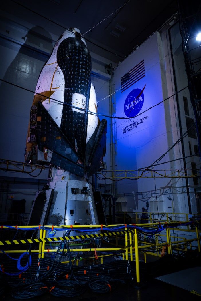 Night-time view of Dream Chaser structural test configuration with dramatic blue lighting highlighting the spacecraft's thermal protection system and NASA facility markings