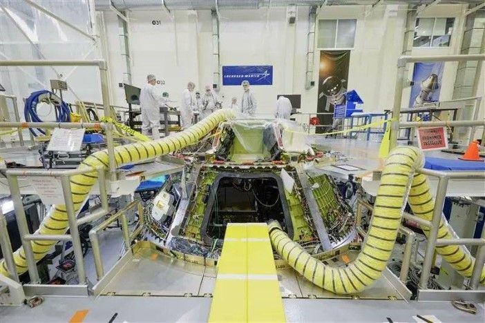 Artemis III Orion spacecraft crew module under construction in clean room with technicians installing flight computers and avionics systems