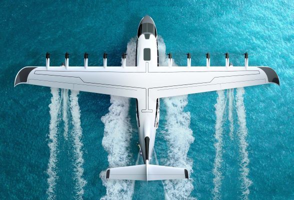 Top-down view of white amphibious aircraft with multiple propellers on wings creating water spray during takeoff or landing