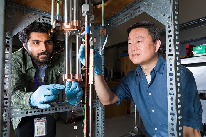 Two researchers in laboratory working with cryogenic testing equipment and copper tubing