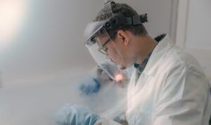 Engineer in protective headgear and face shield working with cryogenic equipment producing vapor