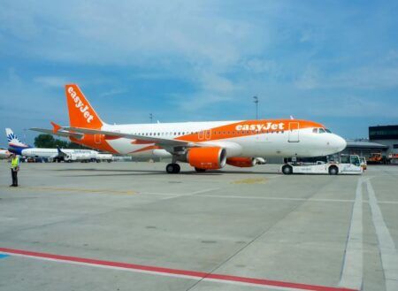 Orange and white easyJet aircraft on airport tarmac with ground support equipment