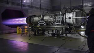 F110 engine undergoes testing in specialized facility with purple exhaust flame visible during operation