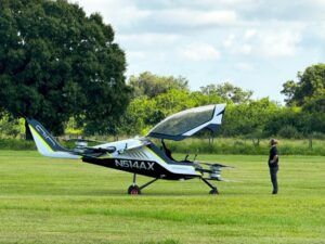 ALT TEXT AIR eVTOL aircraft parked on grass with technician standing nearby