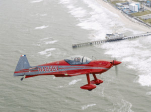 Aura Aero Integral aerobatic training aircraft in flight over Daytona Beach pier
