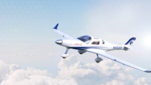 White and blue two-seat electric training aircraft with magniX branding in flight against blue sky