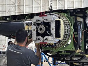Technician inspects electric pusher motor assembly mounted on Eve eVTOL aircraft tail section in hangar facility