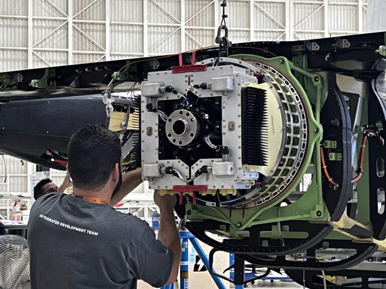 Technician inspects electric pusher motor assembly mounted on Eve eVTOL aircraft tail section in hangar facility