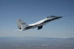 NASA F-15 research jet in flight over the California desert with the CATNLF scale-model wing mounted vertically beneath the fuselage