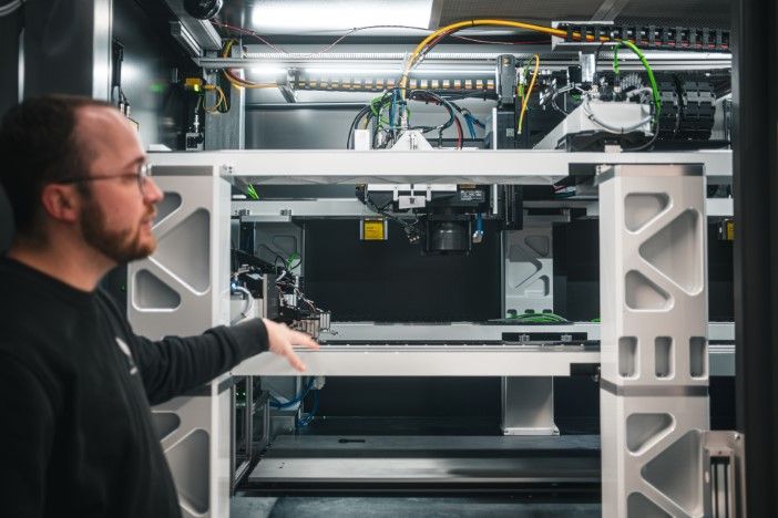 An engineer gestures toward automated battery manufacturing equipment at the Vertical Aerospace Energy Centre