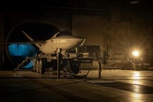 A Kratos Valkyrie uncrewed combat aircraft bearing Airbus markings on a ground support cradle inside a hangar facility