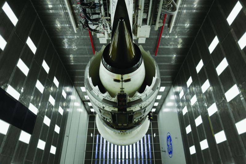 A GEnx-1B commercial jet engine suspended in an indoor test cell at GE Aerospace's Peebles Test Operation in Ohio, viewed from below