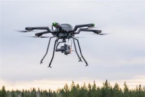 A hexacopter drone equipped with a hyperspectral camera in flight over the tree line at VTT's test site in Finland
