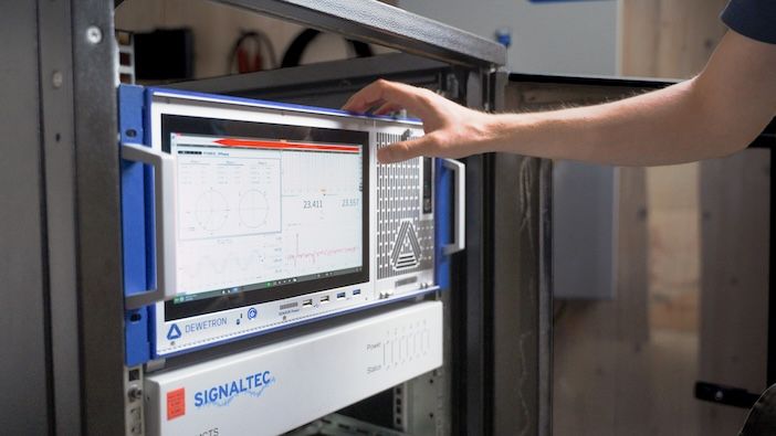 A Dewetron DEWE3-PA8 data acquisition system mounted in an equipment rack displaying real-time measurement data on its integrated touchscreen