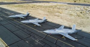 Four YFQ-42A Dark Merlin collaborative combat aircraft lined up on a desert airfield runway