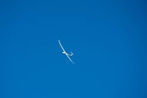 White high-aspect-ratio uncrewed aircraft in flight against a clear blue sky, viewed from below