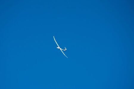 White high-aspect-ratio uncrewed aircraft in flight against a clear blue sky, viewed from below
