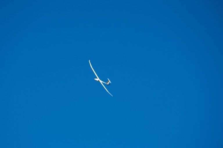 White high-aspect-ratio uncrewed aircraft in flight against a clear blue sky, viewed from below