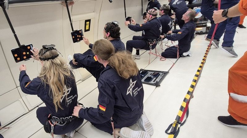 Participants in the University of Magdeburg experiment perform cognitive tasks on tablets during microgravity while wearing vagus nerve stimulation headsets