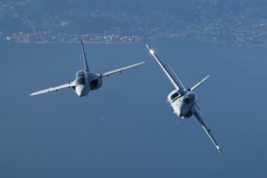 Two Leonardo M-346 advanced jet trainers in loose formation flight over a coastal landscape