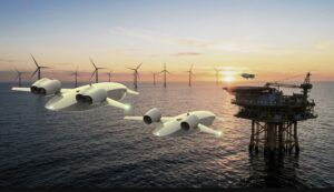 Two Acodyne unmanned eVTOL cargo aircraft flying past offshore wind turbines and an oil platform at sunset