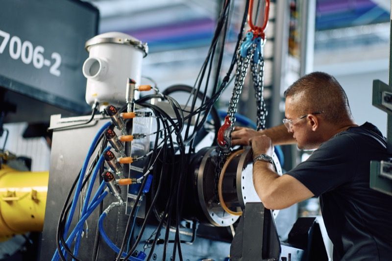 An engineer wearing safety glasses works on an electric power systems test rig fitted with high-voltage cabling and sensors