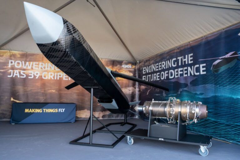 GKN Aerospace unveils Swedish defense drone demonstrator Full-scale uncrewed aerial vehicle mock-up mounted nose-up on a stand beside a turbojet engine on a wheeled trolley inside an exhibition marquee