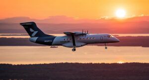 Heart Aerospace X1 electric demonstrator aircraft in flight against an orange sunset sky over water