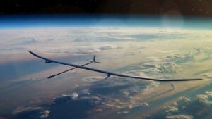 A solar-powered PHASA-35 uncrewed aircraft with a long slender wing flying in the stratosphere high above the Earth, with the curve of the planet and cloud layers below