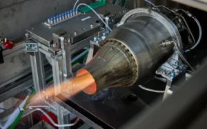 Additively manufactured turbojet engine firing on a test stand with a visible exhaust plume surrounded by instrumentation