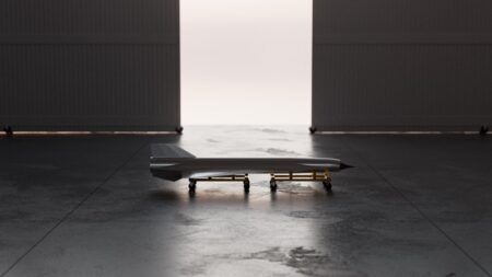 Hermeus reveals air-launched expendable hypersonic testbed Ramjet-X Rendering of the slender, dart-shaped Ramjet-X hypersonic test vehicle on a wheeled cradle in a darkened hangar, with light coming through the open doorway