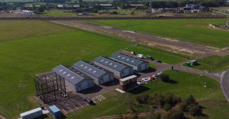 Aerial view of the drone testing facility at Westcott Venture Park, with hangars, a control building, parking and a test area beside a runway in open countryside