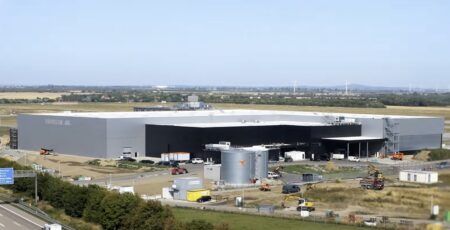Deutsche Aircraft opens D328eco final assembly line in Leipzig, Germany Aerial view of Deutsche Aircraft’s new final assembly line at Leipzig/Halle Airport, a large grey and black hangar complex beside the airfield with construction equipment still on site