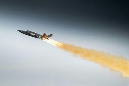 Airbus Valkyrie uncrewed combat aircraft completes maiden European flight Dark grey uncrewed combat aircraft climbing steeply with a bright rocket booster flame and a long orange smoke trail against a grey sky
